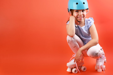 A small child with roller skates and a blue helmet demonstrates positive emotions. A girl of 7 years old poses and prepares for active leisure on retro ice skates. Children's sport concept