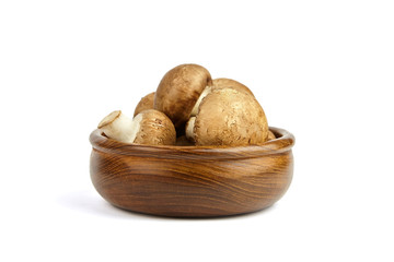 Mushrooms in wooden bowl isolated on white background. Whole fresh brown champignons