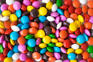 Fototapeta na wymiar Background of multicolored chocolate jelly beans, multicolored sweets base for background