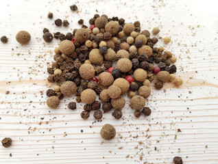 Scattered black pepper, spices on a light background with a wooden texture. Ingredients for cooking.