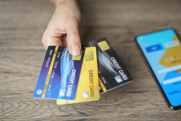 Woman hand showing her many credit card with smart phone for shopping online.