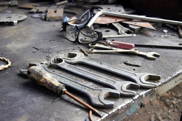 wrenches, screwdriver, protection glasses and other tools on a workbench