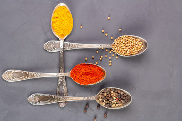 Dry spices of different colors in teaspoons. Top view