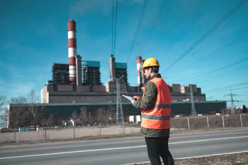 A young engineer in work equipment,controls the progress of work in a thermal power plant