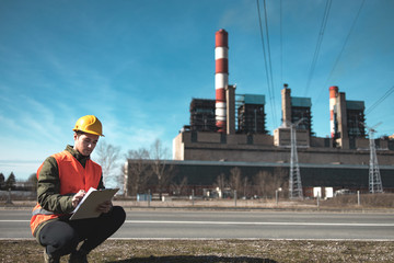 A young engineer in work equipment,controls the progress of work in a thermal power plant