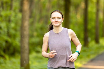 young woman runs in a forest and makes fitness