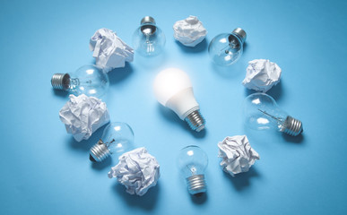 Obraz na płótnie Canvas Light bulbs and crumpled papers on the blue background. Idea