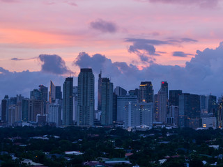 Makati, Metro Manila, Philippines: Afternoon Skyline with pink dramatic sky and clouds and Dasmarinas Village.