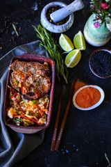 beef steak with rice on dark table with lime, herbs and spices