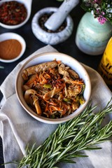 udon noodles with chicken and vegetables, bottle of juice, rosemary and spices on dark table