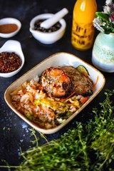 meat steak served with rice and vegetables on dark table with orange juice, herbs and spicies