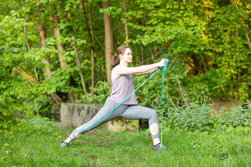 Young woman makes fitness exercises in nature