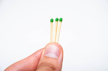 Wooden little matches with a green head. The male hand holds three matches in the hand evenly and...