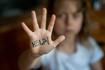 Little girl asks for help, help written on hand. Domestic and child abuse.