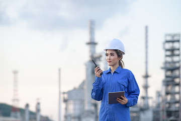 Business women in uniform and helmet young women engineer concept using tablet working on social network with industry background