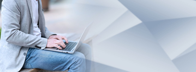 Businessman using laptop outdoors; panoramic banner