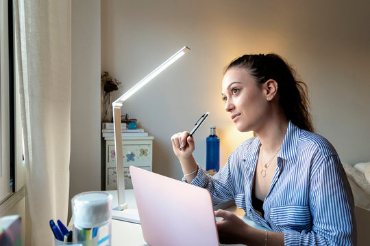 Young attractive female doing homework sitting desktop with modern laptop computer