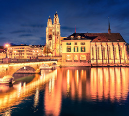 Fototapeta na wymiar Spectacular night cityscape of Zurich city, Switzerland, Europe. Picturesque evening view of Grossmunste - Protestant church reflected in Limmat River. Traveling concept background.