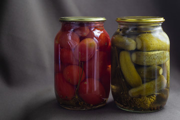 canned cucumbers and tomatoes in glass jars