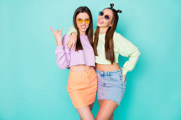 Photo of two funny crazy behavior ladies show horns hands stick tongue out mouth wear sun specs...