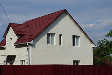 white private house with a window under a red tiled roof against a  sky on a sunny day