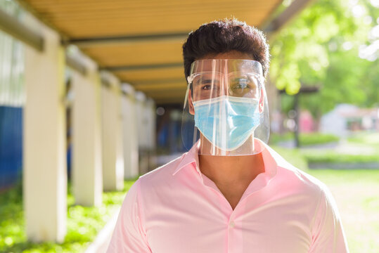 Face Of Young Indian Businessman With Mask And Face Shield At The Park Outdoors