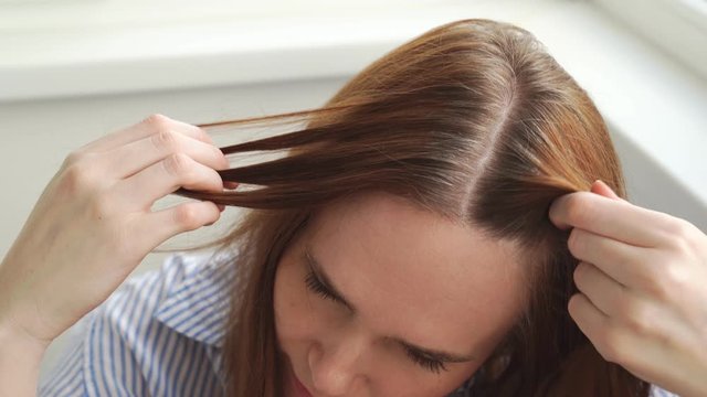 woman shows regrown hair roots. long dyed hair, growing natural color. gray.