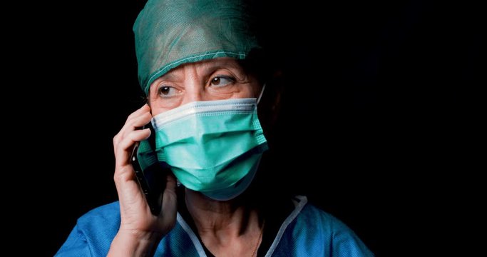 Dottoressa parla al telefono con la mascherina e lo sfondo nero