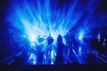 silhouettes of musicians on stage in the rays of light