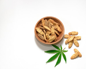 Crisp shortbread cookies with cannabis seeds in a wooden plate on a white background
