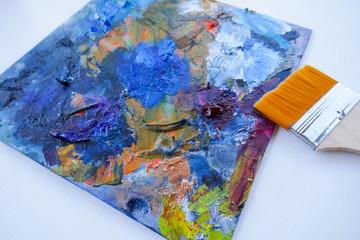Artist, palette with paints, brushes and a palette knife on a white background.