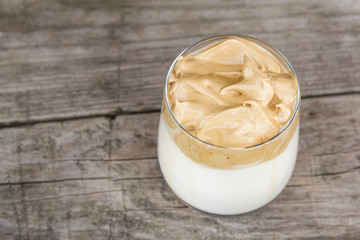 Dalgona coffee on rustic wooden background.