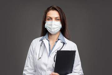 Female doctor in face mask with clipboard