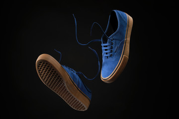 Close up view of levitation blue sneakers shoes with  flying laces over black background with copy...
