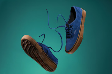 Close up view of levitation blue sneakers shoes with  flying laces over green background with copy...