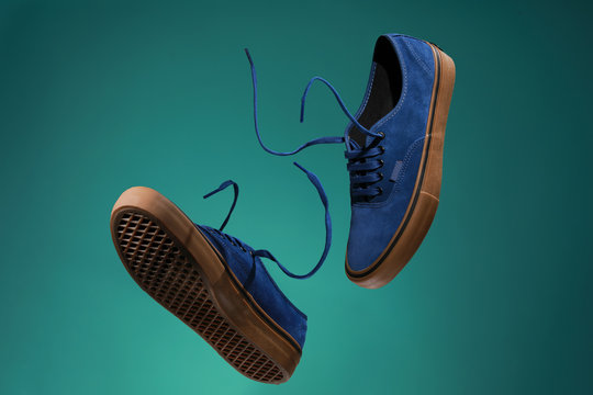 Close up view of levitation blue sneakers shoes with  flying laces over green background with copy space for text. 