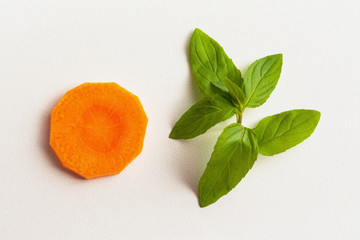 A sprig of mint and a carrot on a white background. Vitamin kit. Ingredients for carrot juice with mint. Isolated carrots and mint. Food preparation. Products on a white background in sunlight.