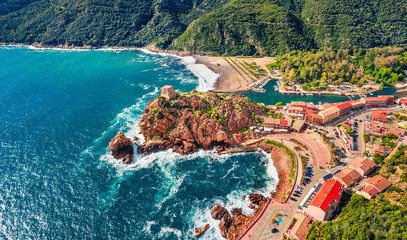 View from flying drone. Incredible summer cityscape of Porto town with Genoise de Porto Ota tower. Aerial morning view of Corsica island, France, Europe. Traveling concept background..