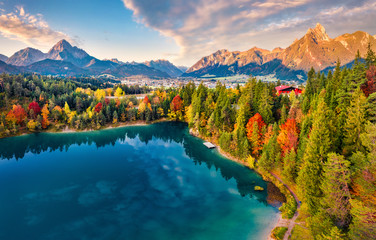 View from flying drone. Majestic morning scene of Urisee lake. Fabulous autumn view of Reutte town, Austria, Europe. Fantastic sunrise in Austrian Alps. Traveling concept background.
