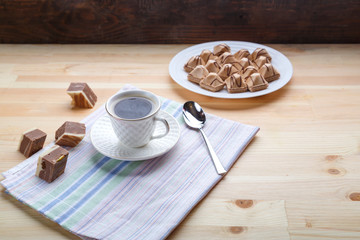 Cup of coffee on napkins on a wooden table with croissants and sweets