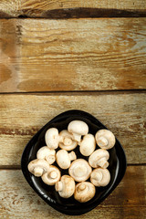Champignons in a black plate on a table of rough boards.
