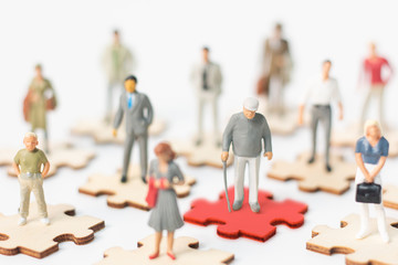 Miniature figures, Infected old person COVID-19 or coronavirus standing on red puzzles and other...