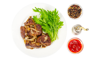 Pieces of fried liver with onions, fresh leaves of salads
