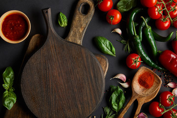 top view of red cherry tomatoes, tomato sauce, peppercorns, herbs and green chili peppers near...