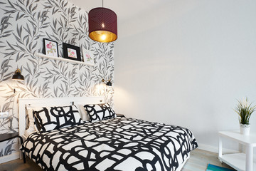 Lights on in the Scandinavian style bedroom with a wooden bed with black and white linen and...