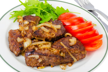 Pieces of fried liver with onions, fresh leaves of salads