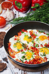 Shakshouka with five cooked eggs on top of tomato sauce in cast iron skillet	