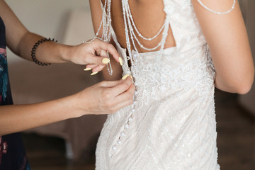Obraz na płótnie Canvas Bride's dress. White bridesmaid dress that help button up girlfriends