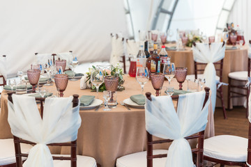 Tables are set for a party or wedding reception. Luxurious elegant dinner in a restaurant. Glasses and dishes and flowers.