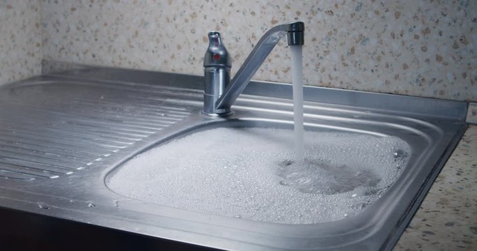 Overflowing kitchen sink with water and foam blockage sin